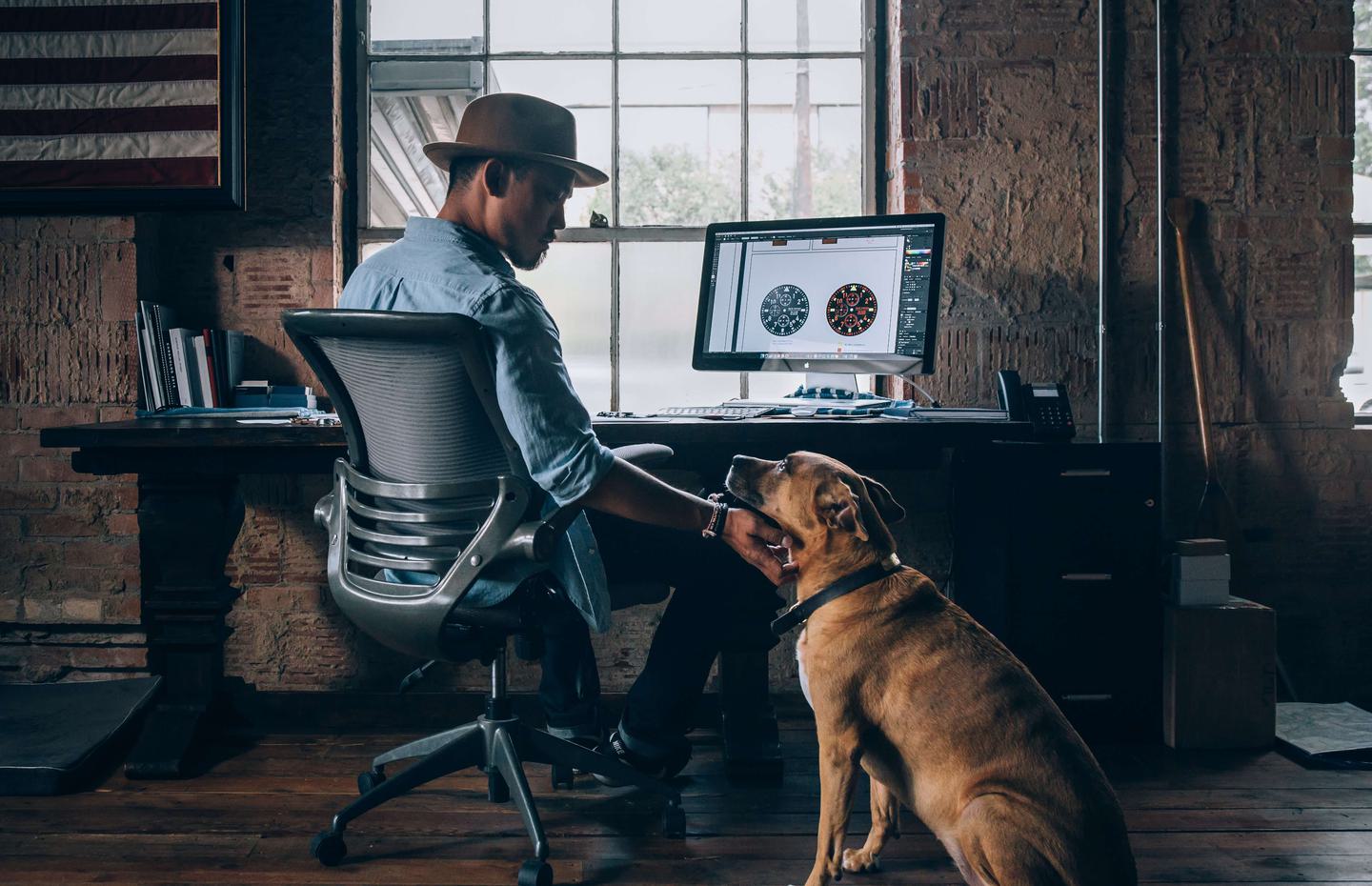 Man working on computer with dog beside him